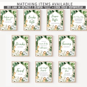 May include: A set of framed signs with jungle animal illustrations and text. The signs feature phrases such as "Babies are Sweet," "Books & Gifts," and "Diaper Raffle." Each sign has a green and gold border with tropical leaves.