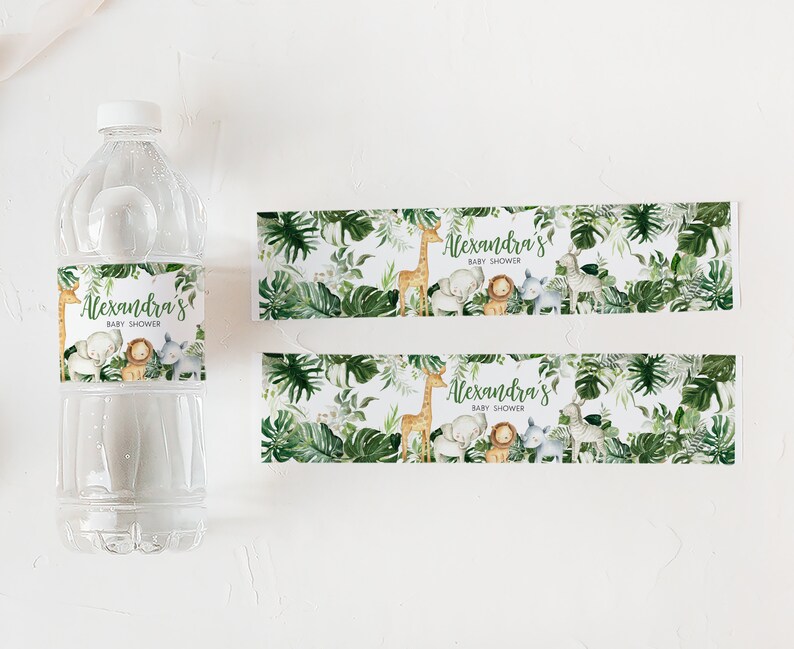 May include: Two printable water bottle labels with a jungle theme. The labels feature a giraffe, elephant, lion, and zebra with green leaves and the text "Alexandra's Baby Shower".