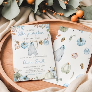 A baby shower invitation featuring a pumpkin theme, with illustrations of pumpkins, leaves, and a baby on a clothesline.