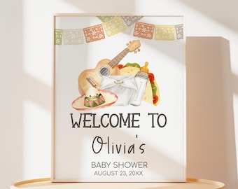 May include: A white welcome sign with a brown wood frame. The sign has a colorful illustration of a guitar, a taco, a baby bottle, and a sombrero. The text on the sign reads "Welcome to Olivia's Baby Shower August 23, 20XX".