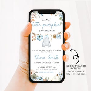A hand holding a smartphone displaying a baby shower invitation with a floral design.