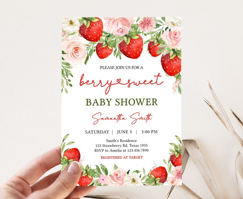 a hand holding a baby shower card with flowers and strawberries