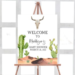 Puede incluir: Un cartel de bienvenida a la fiesta de bienvenida al beb&eacute; de Madison con un tema de desierto. El cartel presenta una calavera blanca con cuernos, cactus verdes y un paisaje des&eacute;rtico marr&oacute;n. El texto dice "Bienvenido a la fiesta de bienvenida al beb&eacute; de Madison 26 de marzo de 2022".