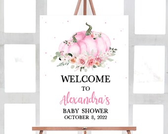 Puede incluir: Un letrero de bienvenida para baby shower sobre un caballete. El letrero presenta una calabaza rosa con detalles florales. El texto dice "WELCOME TO Alexandra's BABY SHOWER OCTOBER 8, 2022".