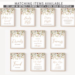 Op de afbeelding: Set van tien printbare borden voor een babyshower met bloemranden en gouden kalligrafie. De borden bevatten "Baby's zijn zoet", "Boeken & Cadeaus", "Luierspel", "Zegt niet baby", "Drankjes", "Help de aanstaande mama", "Favorieten", "Eten", "Late-night luiers" en "Mom-osa Bar".