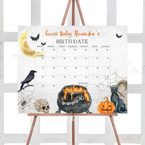 K&ouml;nnte beinhalten: Ein Halloween-Kalender auf einer Holzstaffelei. Der Kalender zeigt ein Aquarelldesign mit Flederm&auml;usen, einem Mond, einer Kr&auml;he, einem Spinnennetz, einem Totenkopf, einem Kessel, einem K&uuml;rbis und einer schwarzen Katze. Der Text enth&auml;lt "Guess Baby Alexandra's BIRTH DATE" und ein Kalenderraster.