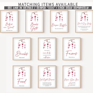 May include: Ten printable signs with a pink and white color scheme. Each sign features a pink and white mobile with hearts and text. The signs include: "Babies are Sweet", "Books & Gifts", "Diaper Raffle", "Don't Say Baby", "Drinks", "Mom-to-be Address", "Favors", "Food", "Late Night Diapers", and "Mom-osa Bar".