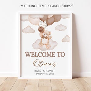 a baby shower sign with a teddy bear holding a balloon