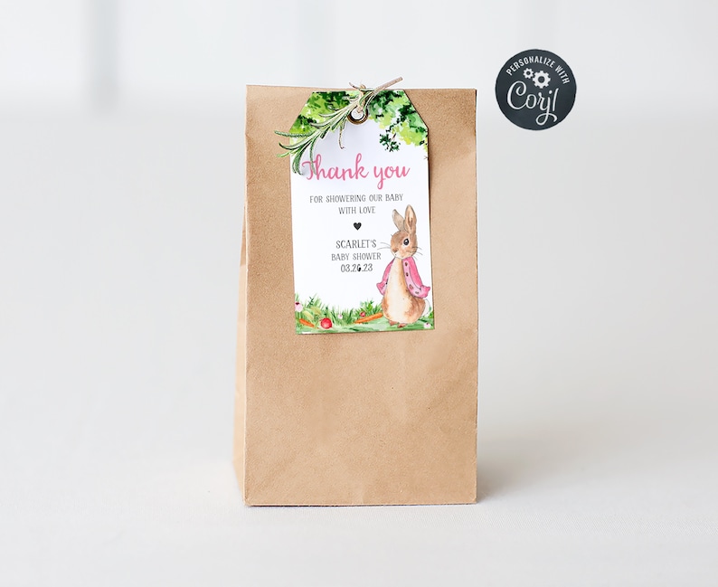 May include: A brown paper gift bag with a thank you tag attached. The tag features a watercolor illustration of a bunny rabbit wearing a pink shawl and surrounded by greenery. The text on the tag reads "Thank you for showering our baby with love, Scarlet's Baby Shower 03.26.23".