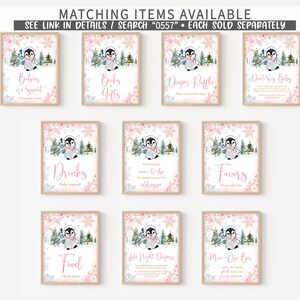 May include: A collection of framed signs with a winter penguin theme. Each sign features a watercolor penguin illustration, pink floral accents, and text such as "Babies are Sweet" and "Drinks". The signs are designed for a baby shower.