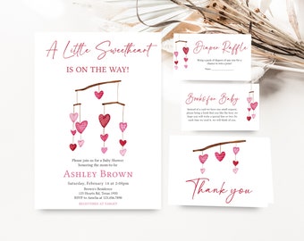 Puede incluir: Una invitación de baby shower rosa y blanca con una ilustración de acuarela de un móvil con corazones rosas. La invitación dice "A Little Sweetheart is on the way!" e incluye el nombre Ashley Brown, la fecha y la hora de la ducha, y la ubicación. La invitación también incluye información sobre la rifa de pañales y libros para bebés.