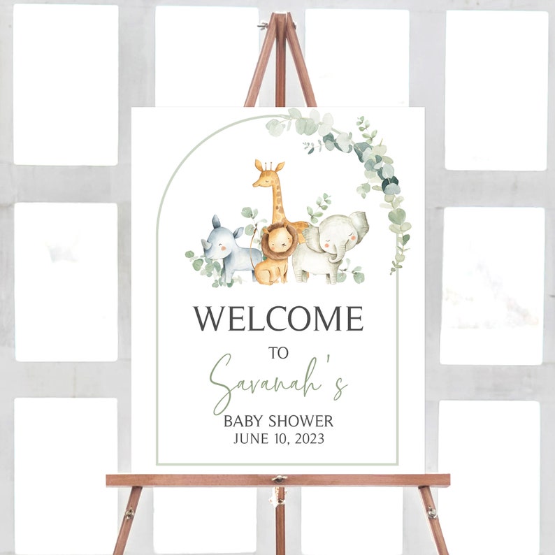 Puede incluir: Un cartel de bienvenida a la fiesta de bienvenida al beb&eacute; de Savannah con una corona de eucalipto verde e ilustraciones de acuarela de una jirafa, un le&oacute;n y un elefante. El cartel dice "Bienvenido a la fiesta de bienvenida al beb&eacute; de Savannah 10 de junio de 2023".