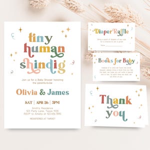 Könnte beinhalten: Ein Babyparty-Einladungsset mit einem verspielten Design. Die Haupt-Einladung zeigt "tiny human shindig" in bunten Buchstaben, zusammen mit den Veranstaltungsdetails. Das Set enthält Karten für eine Windel-Tombola, Bücher für Babys und Dankeskarten.