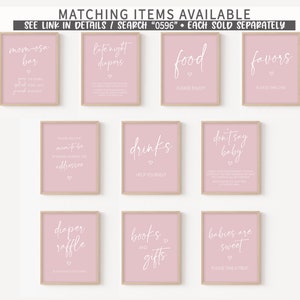 May include: Ten framed pink signs with white text, including phrases such as "Mom-osa Bar", "Late Night Diapers", "Food", "Favors", "Drinks", "Don't Say Baby", "Diaper Raffle", "Books & Gifts", and "Babies are Sweet".