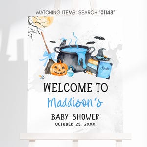The image is a welcome sign for a baby shower, featuring Halloween-themed illustrations such as a cauldron, broom, jack-o-lantern, and bats.