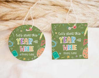 May include: Two green tags with white string, one round and one square. Both have the text "let's start this YEAR off WRITE" in colorful letters, with school-themed illustrations. The text "From: Cara" is also included.