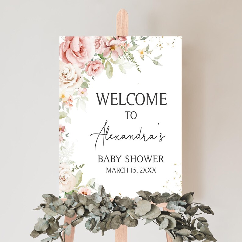 a welcome sign with flowers and greenery on a easel