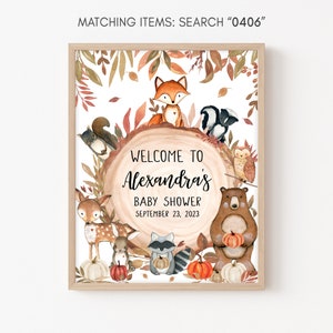 May include: A framed baby shower sign with woodland animal illustrations. The sign reads "Welcome to Alexandra's Baby Shower September 23, 2023." The artwork features a fox, squirrel, skunk, owl, deer, raccoon, and bear, with pumpkins and fall foliage.
