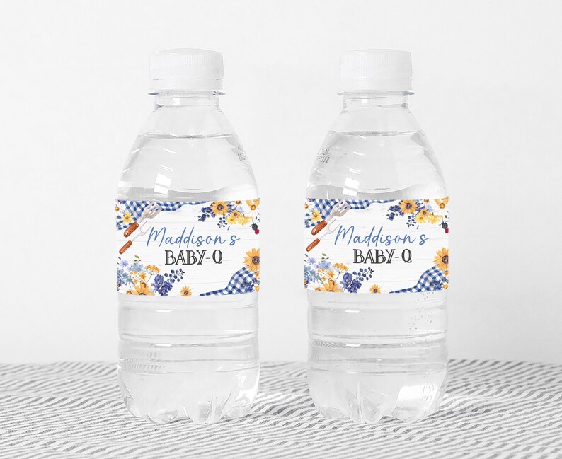 Puede incluir: Dos botellas de agua de pl&aacute;stico transparente con etiquetas de cuadros azules y blancos y flores. Las etiquetas dicen "Madisson's Baby-Q".