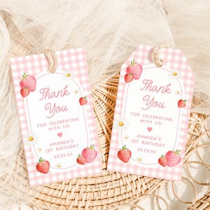 two tags with strawberries on them sitting on a basket