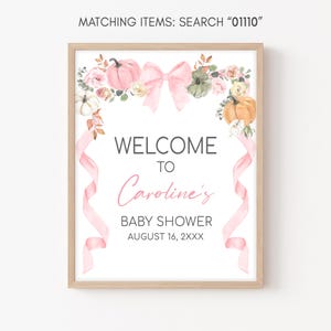 a baby shower sign with a pink ribbon and flowers
