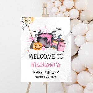 a sign with a Halloween theme, including a witch's broom, a pumpkin, and a cauldron, along with the text "Welcome to Maddison's Baby Shower" and the date "October 25, 2XXX".