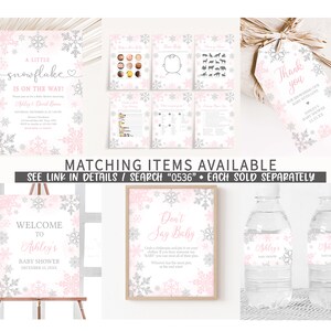 Op de afbeelding: Een verzameling baby shower decoraties met een sneeuwvlok thema. Items zijn onder meer uitnodigingen, spelletjes, een welkomstbord, waterfleslabels en een "Don't Say Baby" bord. Het kleurenschema is roze, zilver en wit.