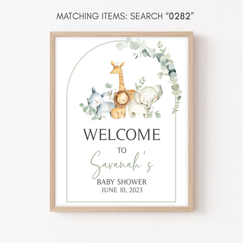 Puede incluir: Bienvenido a la fiesta de bienvenida al beb&eacute; de Savannah con una corona de eucalipto verde y una ilustraci&oacute;n de acuarela de una jirafa, un le&oacute;n, un rinoceronte y un elefante. El cartel est&aacute; impreso en papel blanco y enmarcado en un marco de madera claro.