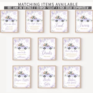 May include: A collection of ten rectangular signs featuring a light purple truck carrying a Christmas tree and woodland animals, decorated with purple floral accents and snowflakes. Each sign displays unique text for event stations and activities.