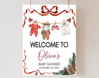 May include: A baby shower sign with the text "Welcome to Olivia's Baby Shower December 20, 20XX." The sign features watercolor illustrations of baby clothes hanging on a clothesline, with red bows and ribbons.