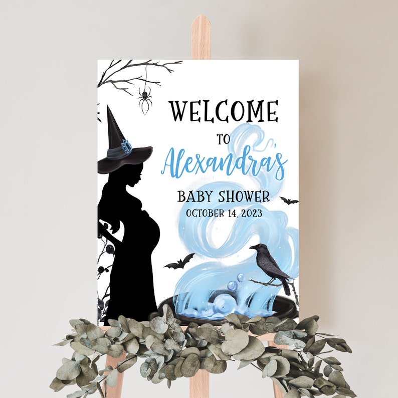 Op de afbeelding: Een welkomstbord voor een babyshower met een silhouet van een zwangere heks. De tekst "Welcome to Alexandra's Baby Shower October 14, 2023" wordt benadrukt met blauwe en zwarte elementen. Een kraai en vleermuizen zijn ook afgebeeld.