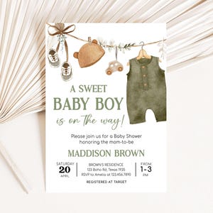 May include: A baby shower invitation with a green and brown color scheme. The invitation features a watercolor illustration of a baby's outfit hanging on a clothesline with a toy car and a hat. The text reads "A Sweet Baby Boy is on the way!" and includes the date, time, and location of the shower. RSVP information and registry details are also included.