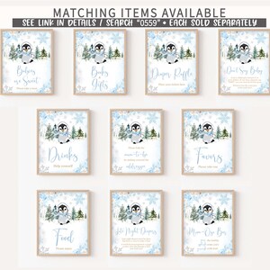 May include: A collection of framed signs with a winter penguin theme. Each sign features a watercolor illustration of a penguin in a scarf, surrounded by snowflakes and trees. Text on the signs includes "Babies are Sweet," "Books & Gifts," and "Diaper Raffle."