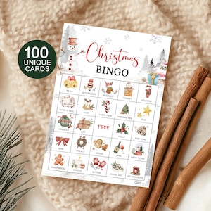 May include: A Christmas Bingo game card with festive illustrations, including a snowman, gifts, and holiday icons. The card features the text "Christmas Bingo" in red script and includes 100 unique cards. Cinnamon sticks and a cozy blanket are in the background.