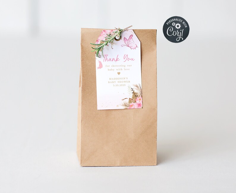 May include: A brown paper bag with a pink and gold thank you tag attached. The tag features a butterfly, flowers, and the text "Thank You for showering our baby with love, Maddison's Baby Shower 1.20.2039".
