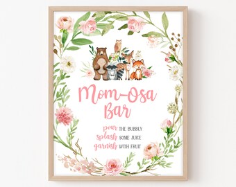May include: A printable sign for a "Mom-osa Bar" with a floral wreath border and woodland animals. The sign says "Mom-osa Bar" in pink text and includes instructions to "pour the bubbly, splash some juice, garnish with fruit".