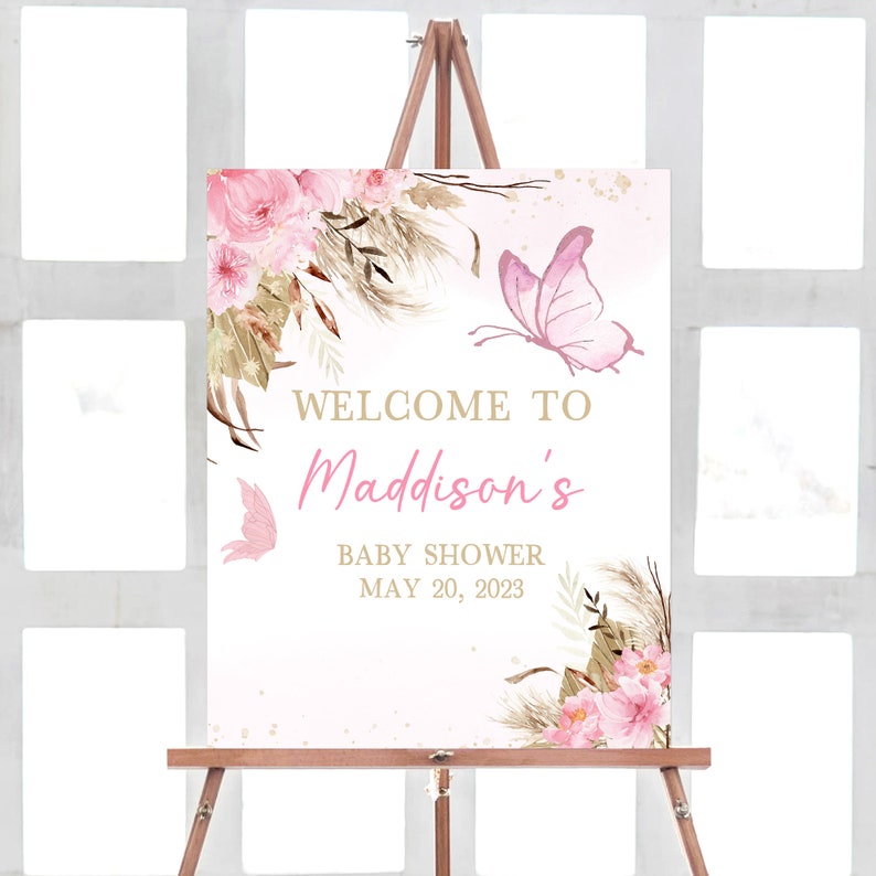 May include: Welcome to Maddison's Baby Shower sign with a pink and gold floral design and butterflies. The date of the shower is May 20, 2023.