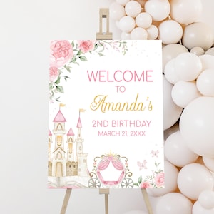 May include: A welcome sign for a 2nd birthday celebration. The sign features a watercolor castle, pink roses, and the text "Welcome to Amanda's 2nd Birthday March 21, XXXX". The sign is displayed on a wooden easel.