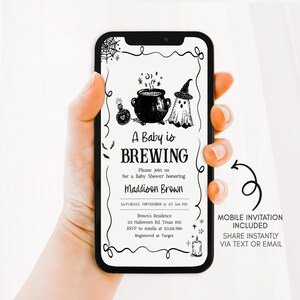 A hand holding a smartphone displaying an invitation for a baby shower.