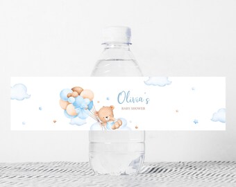 Może przedstawiać: Butelka wody z etykietą na baby shower. Etykieta przedstawia misia z balonami i chmurami. Tekst na etykiecie brzmi "Olivia's BABY SHOWER" w niebieskim skrypcie.