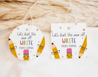 May include: Two white gift tags with string, one round and one square. Each tag features the text "Let's start this year off WRITE FROM: SOPHIA" with colorful pencils, a pink eraser, and stars.