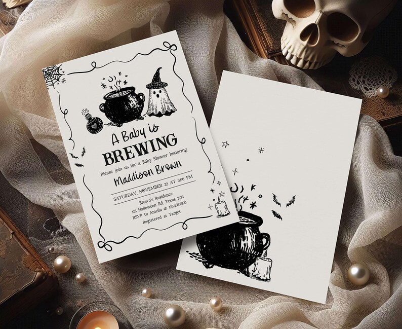 A Halloween-themed baby shower invitation featuring a black and white design with illustrations of a baby, a witch, and a cauldron.