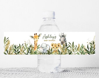 May include: Water bottle label with a jungle theme. The label features a giraffe, zebra, elephant, and lion with green leaves and gold glitter. The text on the label reads "Ashley's Baby Shower".