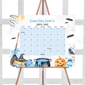 The image is a calendar for a baby's birthday, featuring Halloween-themed illustrations and decorations.