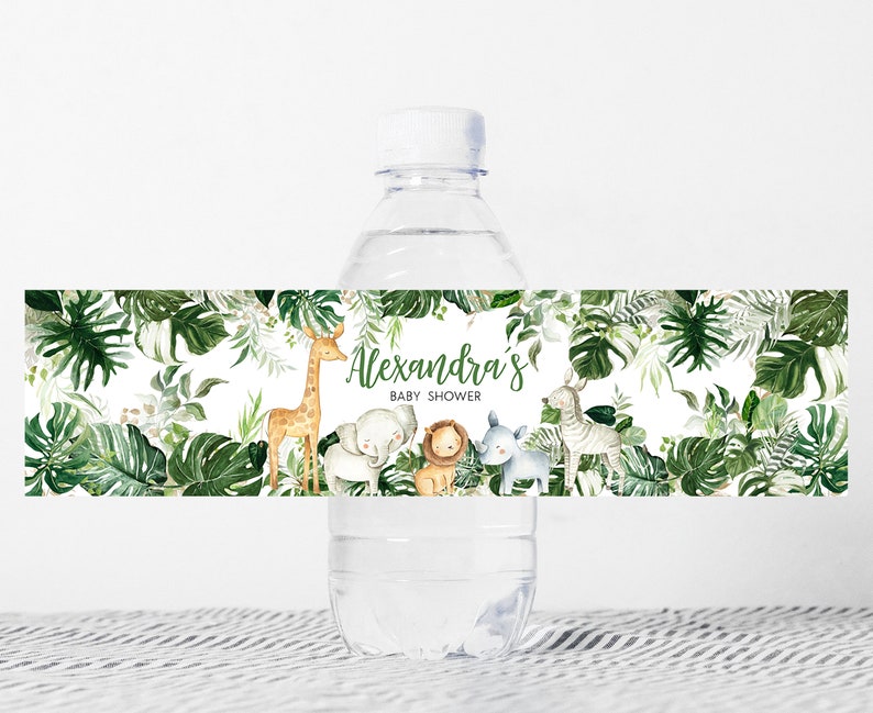 May include: Water bottle label with a jungle theme. The label features a giraffe, elephant, lion, and zebra surrounded by green leaves. The text on the label reads "Alexandra's Baby Shower".