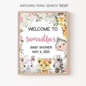 May include: A welcome sign for a baby shower with a pink floral border and a white background. The text reads "Welcome to Samantha's Baby Shower May 6, 2023". The sign features illustrations of a giraffe, monkey, rhino, lion, and zebra.