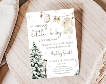 May include: A baby shower invitation with the text "a merry little baby is on the way!" features a watercolor illustration of baby clothes, a snowy pine tree, and a street lamp. The invitation includes the date, time, and location.