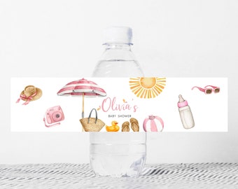 Puede incluir: Etiqueta de botella de agua con una sombrilla a rayas rosa y blanca, un pato de goma amarillo, una pelota de playa rosa y blanca, un biberón rosa, gafas de sol, una cámara, un sombrero de paja y el texto "Olivia's Baby Shower".