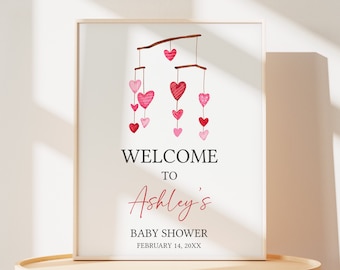 Könnte beinhalten: Ein druckbares Babyparty-Schild mit einem rosa und roten Herz-Mobile-Design. Das Schild lautet "Willkommen zur Babyparty von Ashley am 14. Februar 20XX".