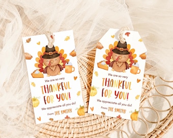 Peut inclure: Deux étiquettes cadeaux sur le thème de l'Action de grâce avec une dinde de dessin animé portant un chapeau de pèlerin. Les étiquettes indiquent "We are so very THANKFUL FOR YOU!" avec du texte supplémentaire et sont décorées de citrouilles, de tarte et de feuilles.